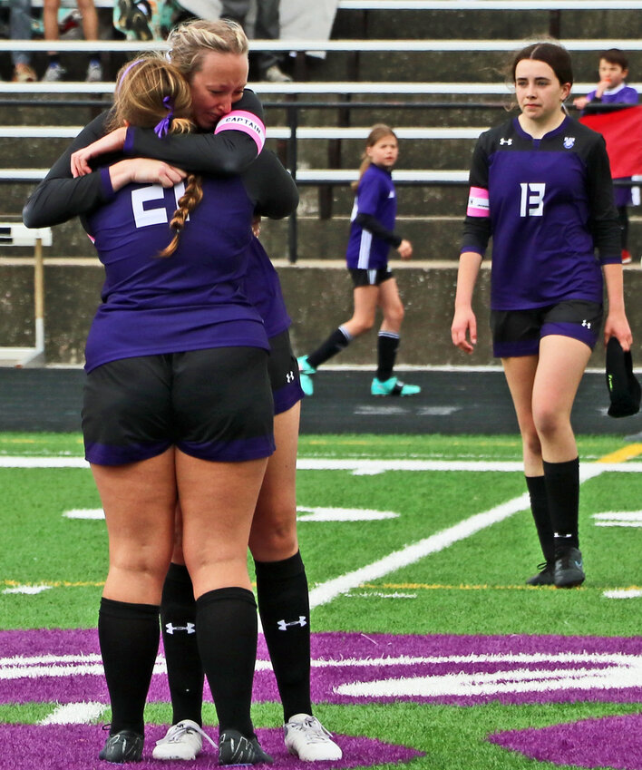 Blair senior Marin Sather, left facing, embraces classmate Wrylee Osterhaus at the end of their final scocer match Saturday at Vets Field. Senior Katie Kramer (13) reacts, too, after the Bears lost 4-2 to Columbus Scotus during the district final round.
