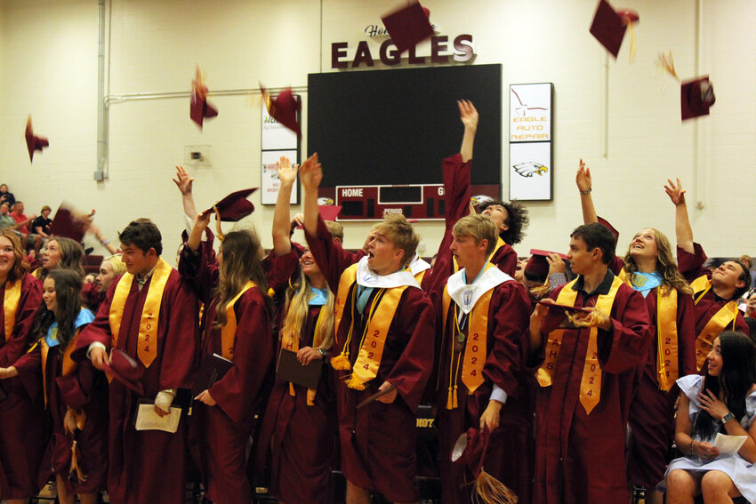 Arlington High School graduates throw their caps in the air at the conclusion of graduation Sunday afternoon.