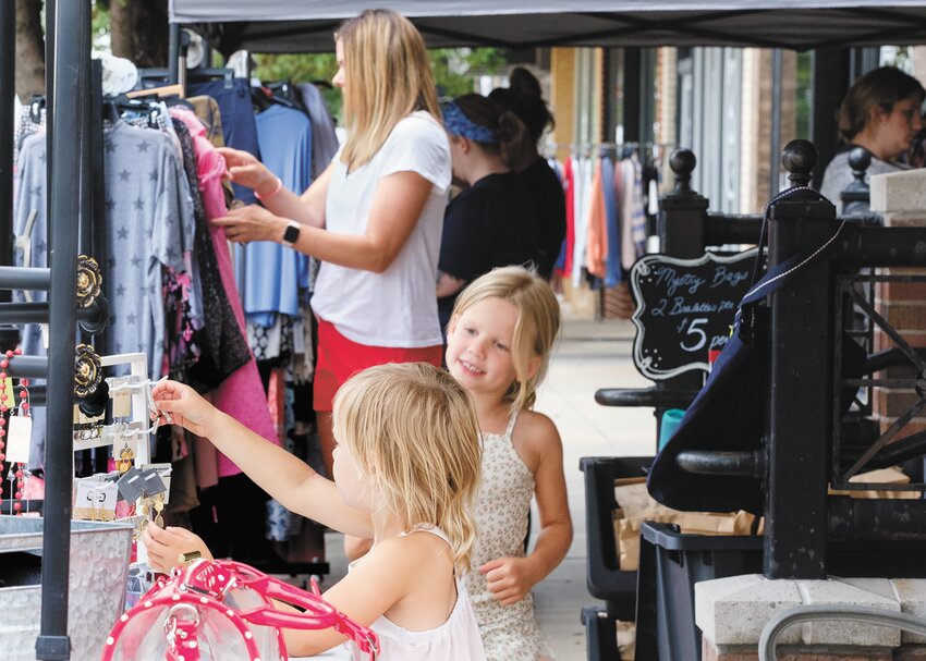 Harper and Peyton Greve look at jewelry while mom Lacy in background browses a clothes rack at Bra-Ta Boutique during last Saturday's Blair Sidewalk Sale.