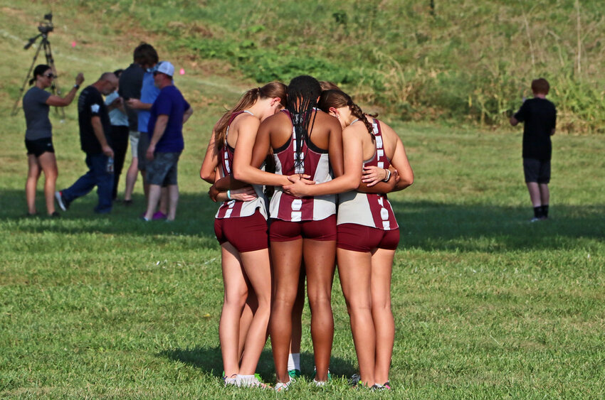 Arlington cross-country runners share a moment together Thursday before the girls' race at the Washington County Fairgrounds.