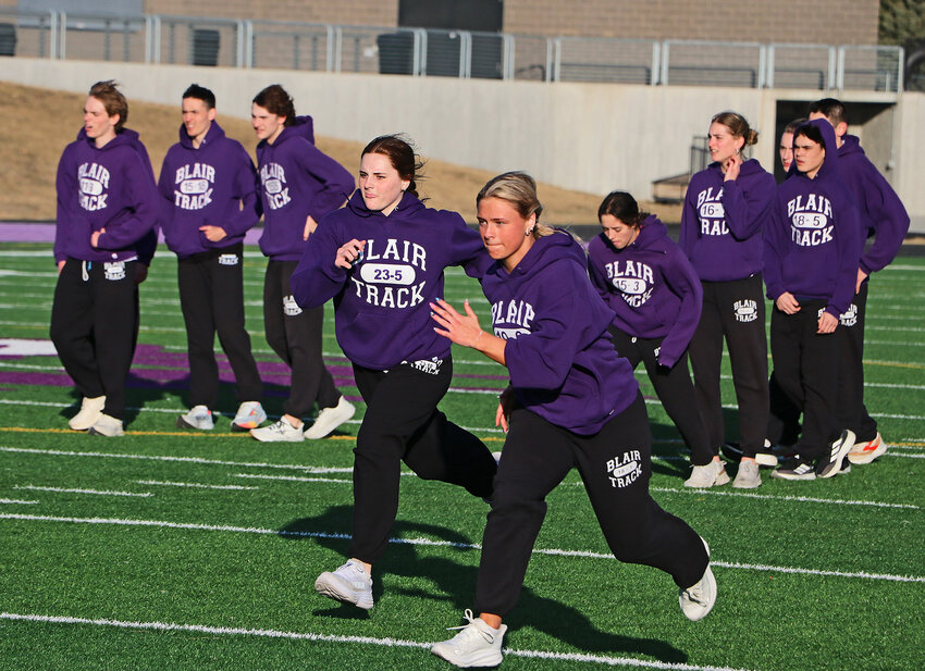 Blair High School's Haylie Jensen, middle left, and Brynn Lundgren, middle right, warm up with their teammates Friday during track and field practice at Krantz Field.