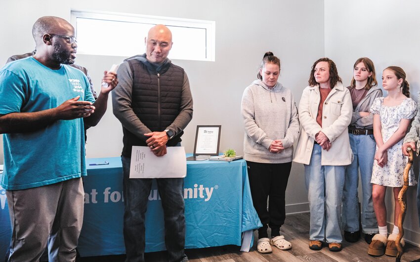 From left, Habitat Mortgage Loan Associate Allen Guidry and Habitat Area Director for Washington County Ken Mar, introduce the new homeowners and deliver opening remarks during the dedication event last Friday.