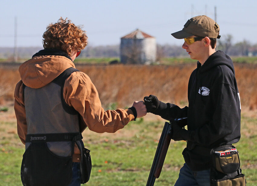Greyson Nixon, left, and Ryan Banta bump fists Saturday during an ECTC shoot at the Blair Youth Shooting Sports range.