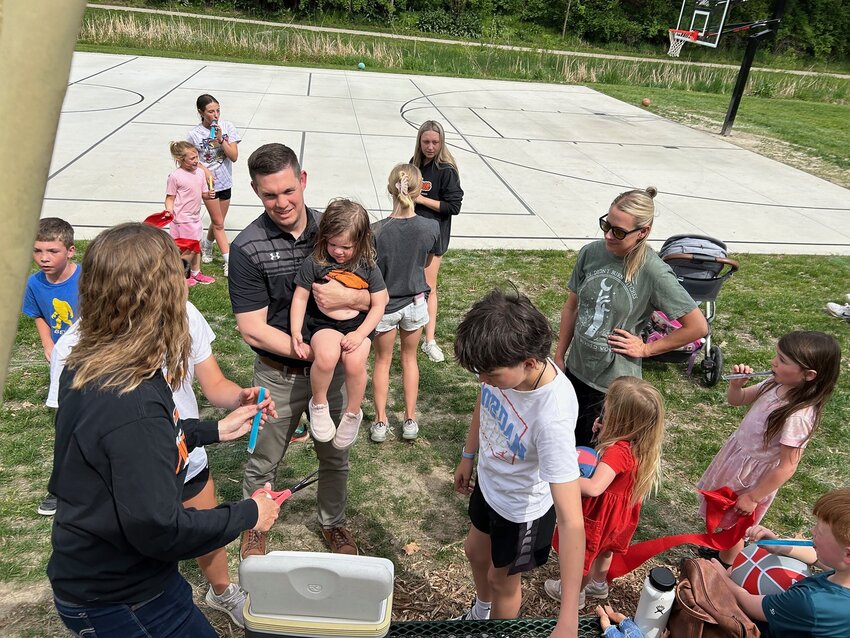 Fort Calhoun Mayor Mitch Robinson (holding ribbon, far left), Parks Board President Kris Richardson (center, with scissors) and Ben Ruthven, President and Owner of Peitzmeier Demolition (holding ribbon, far right), were joined by sponsors and excited children at the official ribbon-cutting ceremony for the Fort Calhoun Pioneer Park multipurpose Court last Wednesday.