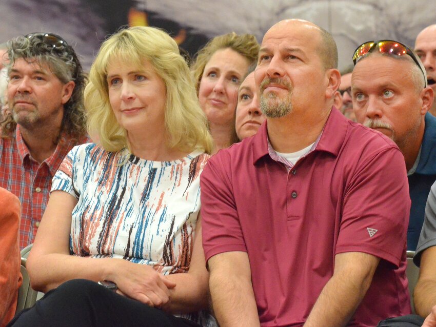 (Above) Graduates Hannah Goodwater, Britt Nielsen and Timothy Halley enjoyed a video montage of their school years during the AHS 2025 Commencement. (Below) Amy and Robert Vanek, parents of graduate Jacob Vanek, and other audience members seemed more wistful as the images rolled by.