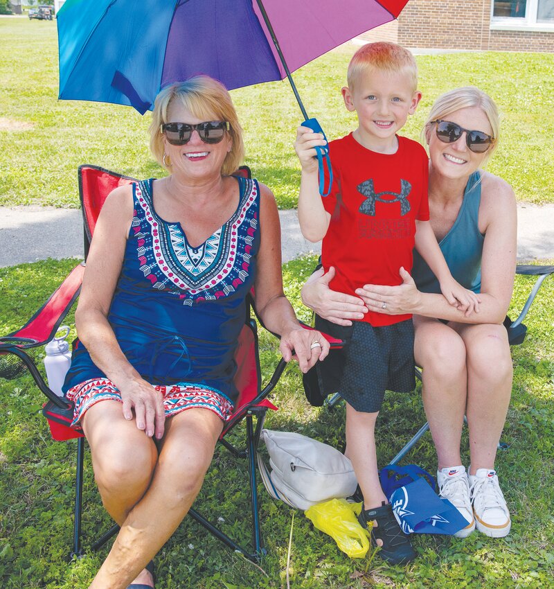 Tre Pleiss keeps his Grandmas Diane Bacon and mother Tonya Pleiss cool with the umbrella for the parade.