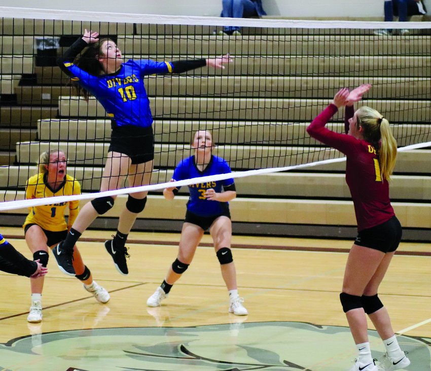 Alice Warne jumps up to knock down a spike with Ava Malone and Marissa Rober looking in anticipation to see what happens while Cori Birkel is ready to block.  Read about the Lady Divers and Lady Bulldogs match up in next week&rsquo;s edition!