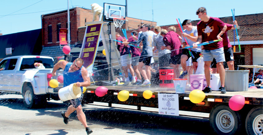 Dave Van Regenmorter is outnumbered while attempting to fire back at De Smet's championship boys basketball team, who were busy soaking the crowds from their float during the Old Settlers Day Parade.