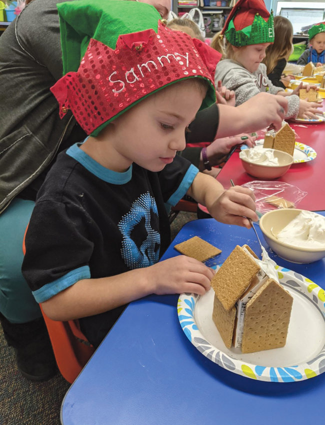 Sammy Bretz, preschooler at Iroquois, builds his gingerbread house with royal frosting.