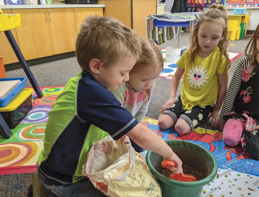 Iroquois preschoolers listened to the book &quot;The Missing Mitten Mystery&quot; by Steven Kellogg. Afterward, Sammy Bretz, left, Raea Guthmiller and Savannah Driggers planted a mitten, hoping it will grow into a mitten tree.