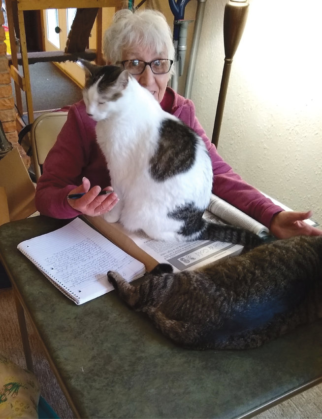 Kingsbury Journal volunteer Mary Rockino is busy working on her weekly column while her assistant Sasha helps. But Clyde, the proofreader, is asleep on the job!
