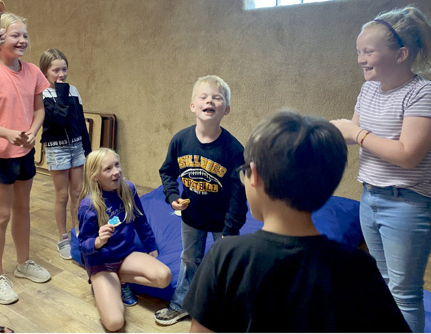 Youth at a recent Illuminate meeting enjoy singing a song at snack time. Clockwise from L-R: Cora Wilkinson, Adilynne Schaefer, Gracyn Wienk, Carter Buckmiller, Hadley Buckmiller and Archer Hart (back to camera.)