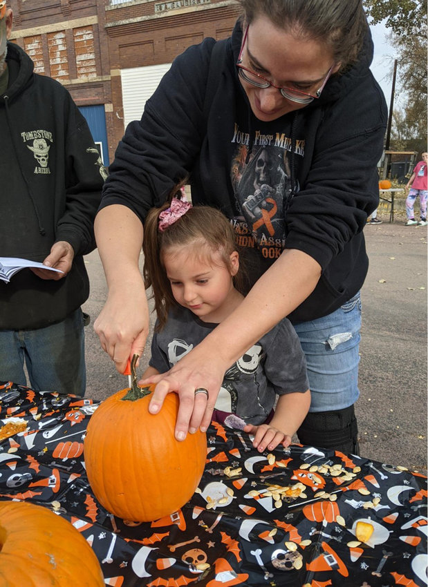 One activity at the festival was pumpkin carving. Josie Downey carves a pumpkin while daughter Willow watches.