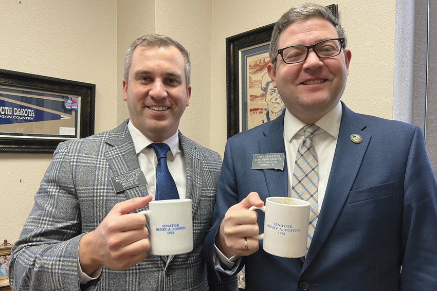 Sen. Casey Crabtree (left) of District 8 and Rep. Tony Venhuizen (right) of District 13, both holding coffee mugs that belonged to Henry A. Poppen of De Smet, former state senator. Poppen represented Kingsbury County and the surrounding area in the Senate for 26 years, from 1967-92. Rep. Venhuizen is Poppen&rsquo;s grandson and is serving his first term in the House. Sen. Crabtree, a native of Arlington, is the Senate Majority Leader and is the first Kingsbury County native to represent the county in the Senate since Poppen.