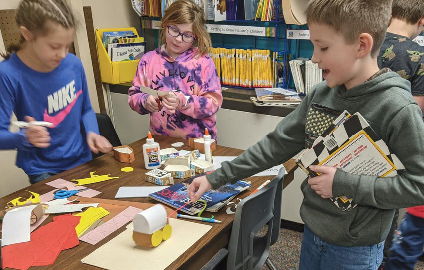 Iroquois Elementary library scholars celebrate a different author each month.  Laura Ingalls Wilder is the February author of the month. The students have been listening to excerpts from the Little House books and participating in related activities.&nbsp;Above: Fourth graders Brianna Blue, left, Maddie Cribben and Drake Perry make miniature covered wagons.&nbsp;