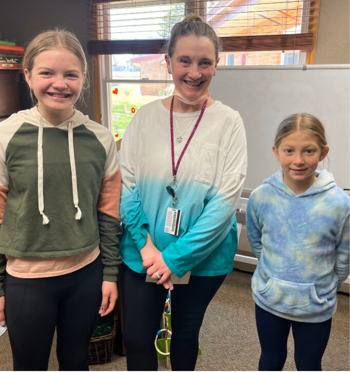 Fourth graders Cora Wilkinson, left, and Clara Palmlund presented a check for $890 to Debra Foley, middle, Activities Director at the Good Samaritan Society. The money was raised through a penny war that Mr. Julius, school counselor, organized in the elementary. The 4th grade class won the competition.