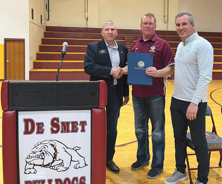 Sen. Casey Crabtree, right, and Rep. Tim Reisch, left, presented a House Commemoration to Coach Jeff Gruenhagen in honor of the 2020-21 and 2021-22 boys basketball championship teams. The commemoration passed in the 2023 legislative session, prior to the Bulldogs winning their third consecutive title.