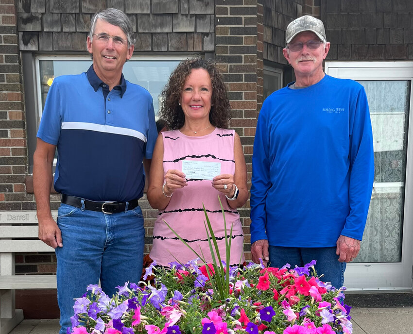 Lorenda Anderson (center) holds the check that she and her husband John (left) gave to De Smet Cemetery treasurer Norm Whitaker (right) with money raised from their recent rummage sale.