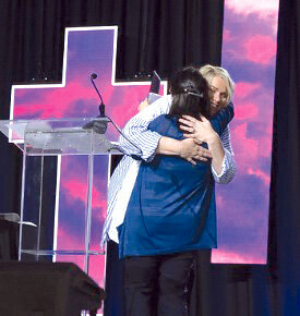 Pastor Tia Felberg (in the white shirt) receives a congratulatory hug from Rev. Rebecca Trefz, the Southeast District Superintendent and Director of Ministries, Dakotas United Methodist Church.