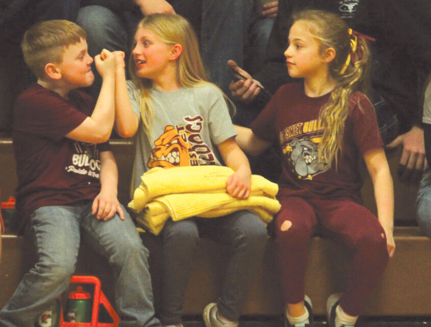 Kylan Botkin, Jaelynn Olson and Brinley Wilkinson make use of some down time on the bench during Friday night&rsquo;s contest between De Smet and Oldham-Ramona-Rutland.