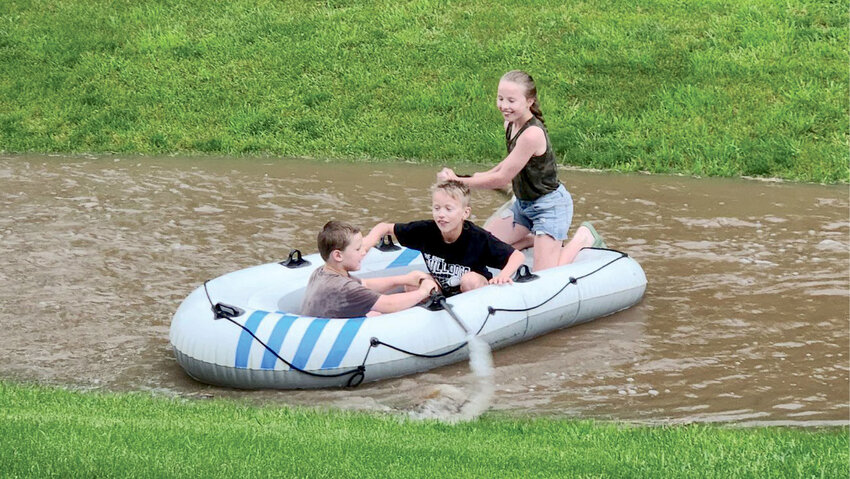 Parker Crowe, left, Miles Albrecht and Ivy Albrecht had a great time rafting in neighborhood ditches after heavy rain on Thursday evening. Severe storms rolled through the northern part of Kingsbury County Sunday evening. Storm clouds left a path of destruction in several areas, including damage at Lake Poinsett.