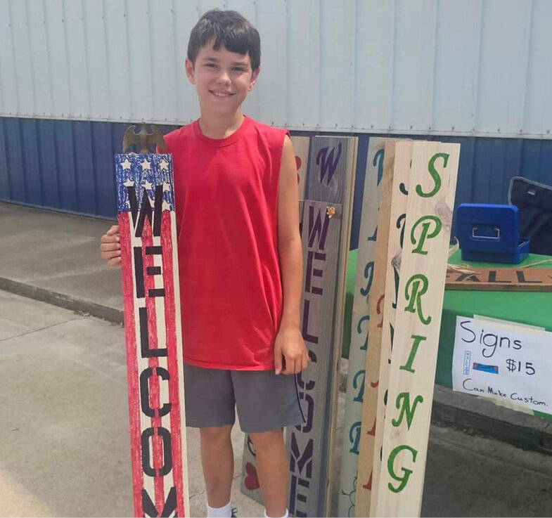 Leo Begnaud stands with the handmade signs he was selling at the Lake Preston farmers&rsquo; market on Fri., July 19.