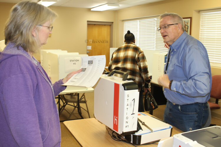 Peg Hamlett, administrator of elections, receives her ballot from election worker Billy Barlow.