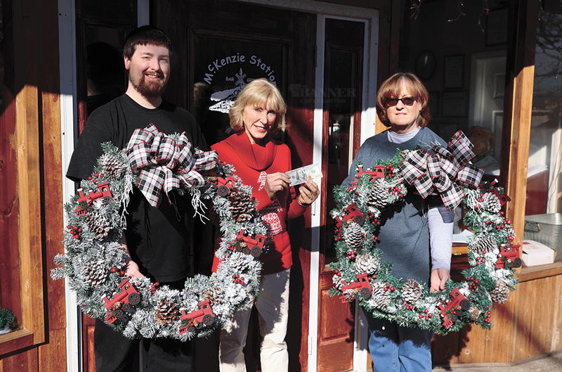 Mayor Jill Holland, center, bestowed Brad and Denise Sam their $100 cash prize, donated by an anonymous donor, for winning Downtown McKenzie&rsquo;s wreath contest.