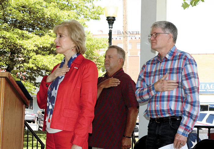 Mayor Jill Holland, Billy Hollowell, and Mike Creasy salute the American flag as the National Anthem is performed.