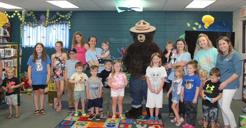 Children, parents, and library staff gather around Smokey Bear.