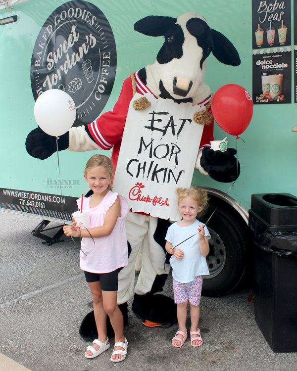 Clara and Emma Currence pose with the Chick-fil-A cow while in line for the Sweet Jordan&rsquo;s food truck.