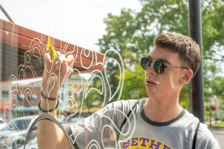 Bethel freshman Dimitrije Stojanovic, newly arrived from his home country of Serbia, is helping to paint a mural in downtown McKenzie August 22, 2022. The mural Dimitrije is painting is one of dozens spread across town, all Bethel themed for some university pride.