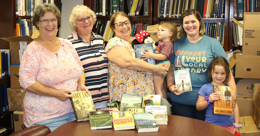 Kim Wester, DeeAnn Roome, Patricia Crockett, Erin Crockett and her daughters, Isadora and Penny Crockett show a few of the books available for purchase during the Bake and Book Sale on September 1-3.