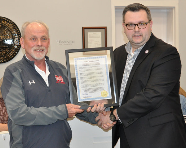 McKenzie Football Head Coach Wade Comer accepts a framed proclamation of behalf of his staff and players from Mayor Ryan Griffin.