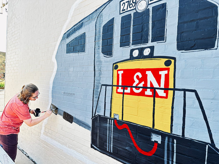 Allison Bowers paints a mural on the side of the Park Theatre in downtown McKenzie.