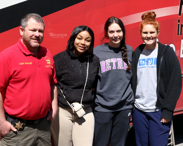 Pictured are Andy Weaver, Student Resource Officer, Taniyah Diggs, Briley Auvenshine, and Payton Ognibene standing outside the Lifelife Bloodmobile.