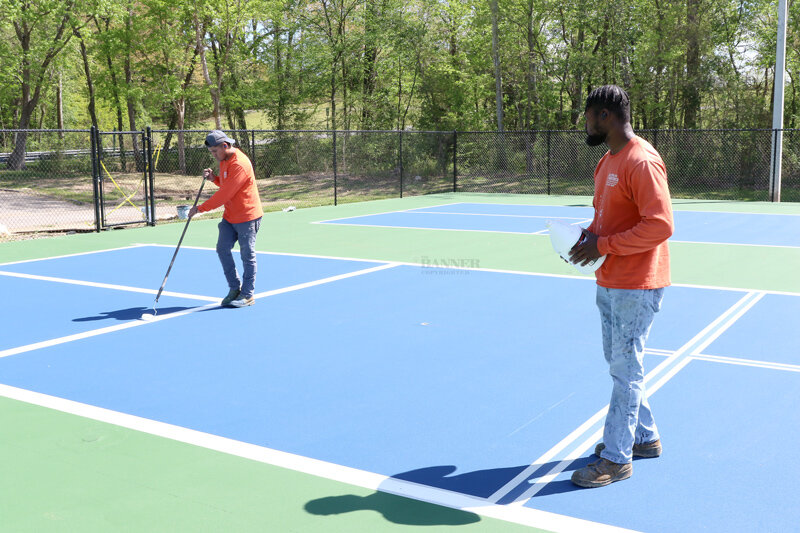 Harvie Halliburton and Salvador Bazquez of Seal Rite/Sports Rite of Tullahoma put the finishing touch on the pickleball courts at McKenzie City Park.