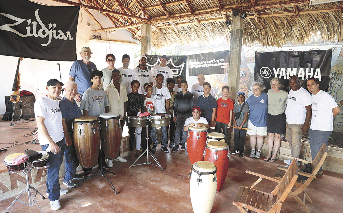 During the educational workshop, members of a local Cuban salsa band assisted Global Citizen Adventure Corps Co-Founder and percussionist Julie Hill. Students enjoyed the new equipment and t-shirts provided by Innovative Percussion, Remo Corporation, Yamaha Corporation, and Zildjian Cymbals and transported to the rural site by the GCAC team. Seen here are (back row, left to right) Robert Miller, Stacie Freeman, Dennis Est&eacute;vez, Yoandi G&oacute;mez, Braydis Rodr&iacute;guez; (front row, left to right) Royet Marquez, Mauricio Roque Piney, Diosmel Pablo Miranda, Keyla Reinoso Acosta, Mia de las Mercedes Antiguas, Daniel Ra&uacute;l Chala, Mauro Luis Barrizonte, Jan Manuel Hondares Cort&eacute;s, Samuel de Jes&uacute;s Ram&iacute;rez, Osvaldo Revuelta Delgado, Lazaro Osniel Correa, Jesus Hernandez, Lynn Alexander, Julie Hill, Lazaro Rivero, Yaniel Lewis, Elier Gonzalez (kneeling). Photo by Joel Washburn/The Banner.