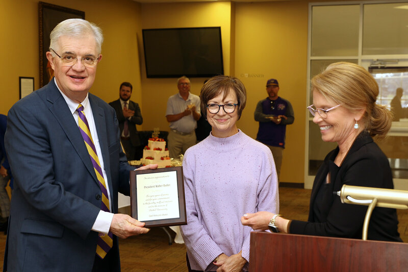 Cindy Mallard (right) presented a plaque to President Walter Butler and wife, Jennifer.