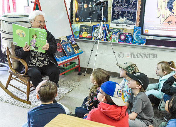 Retired teacher Teresa Norton reads to first graders in her old classroom.