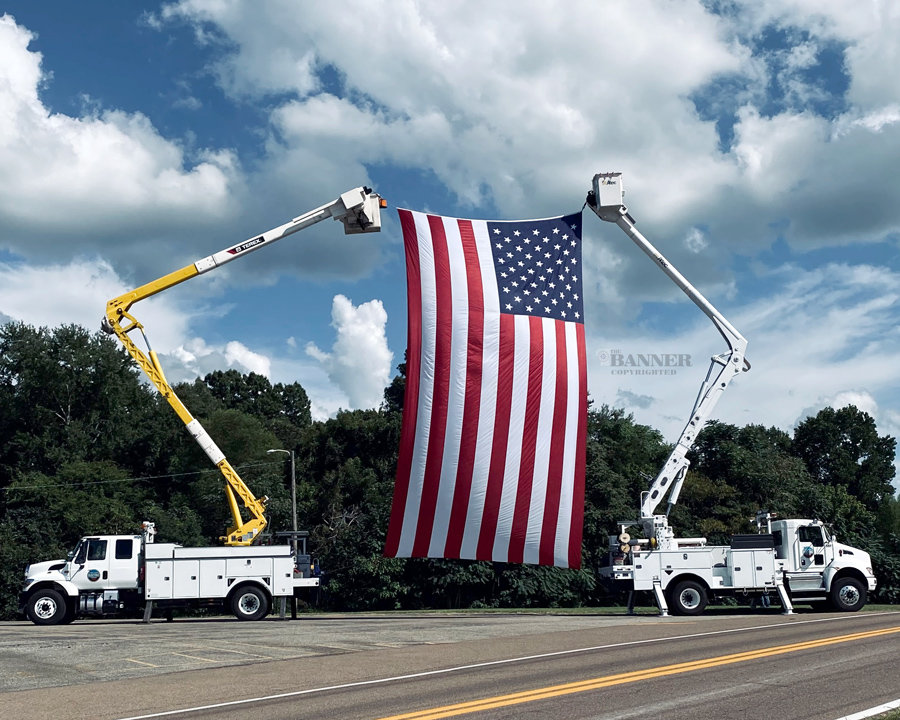 Carroll County Electric Department uses bucket trucks to suspend a giant American flag.