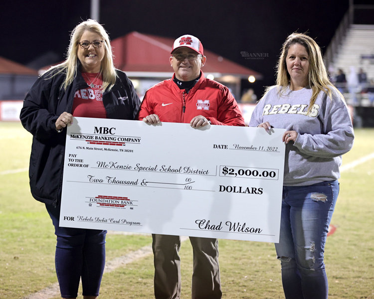 At the half, McKenzie Banking Company representatives Shawna Fowler and Lisa Stewart present a $2,000 check to McKenzie High School Principal Kelly Spivey.