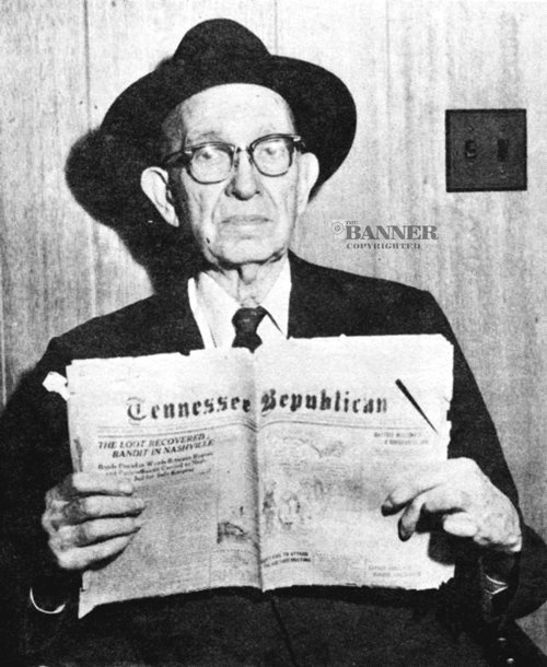 Former Carroll County Sheriff Sam Kennon holding a copy of the Tennessee Republican newspaper from 1923. The headline reads, LOOT RECOVERED: BANDIT IN NASHVILLE.