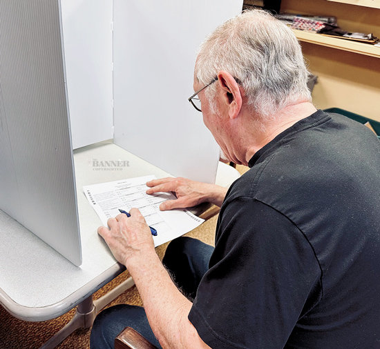 Michael Corrado, one of the election commissioners, marks his paper ballot with an ink pen prior to it being placed in the scanner to record the vote.