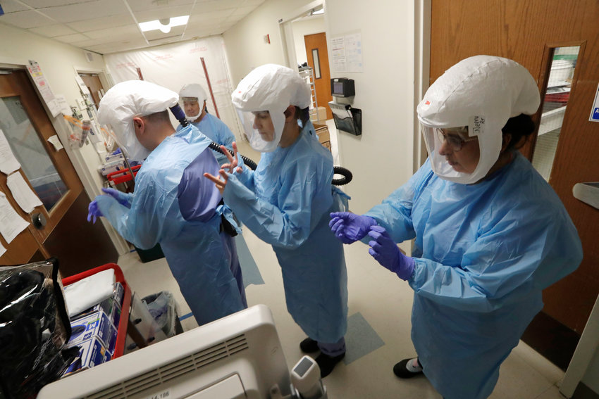 FILE - In this May 8, 2020, file photo, a team of medical workers wearing respirators and protective gear ready to enter the room of a patient in the COVID-19 Intensive Care Unit at Harborview Medical Center, in Seattle. The number of deaths in Washington because of the coronavirus has reached 1,000, the Washington State Department of Health reported Saturday, May 16, 2020. The agency added eight more deaths and listed the total number of confirmed cases at 18,288. (AP Photo/Elaine Thompson, File)