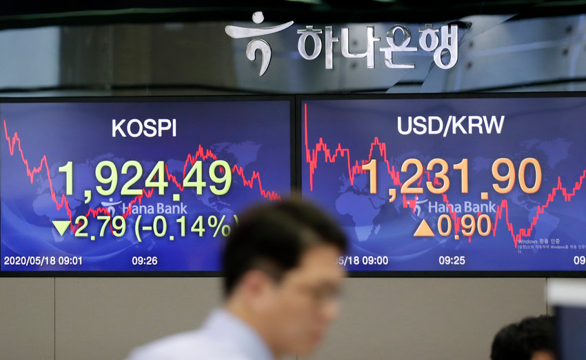A currency trader walks near the screens showing the Korea Composite Stock Price Index (KOSPI), left, and the foreign exchange rate between U.S. dollar and South Korean won at the foreign exchange dealing room in Seoul, South Korea, Monday, May 18, 2020. Asian stock markets rose Monday after the chief U.S. central banker expressed optimism the the American economy might start to recover this year from the coronavirus pandemic. (AP Photo/Lee Jin-man)