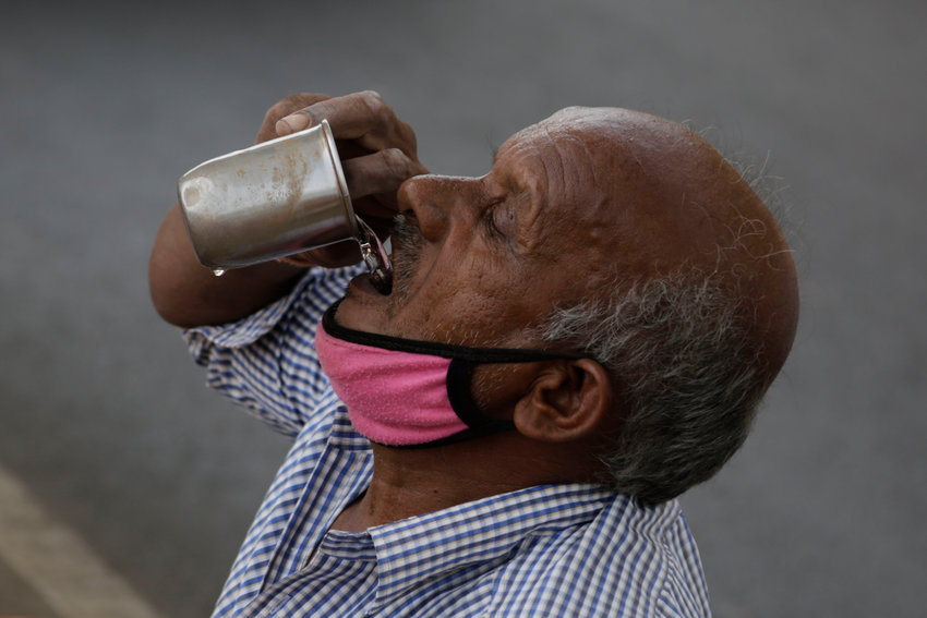 An Indian man drinks water as he sell earthen pots on a road in Ahmedabad, India, Thursday, May 28, 2020. (AP Photo/Ajit Solanki).