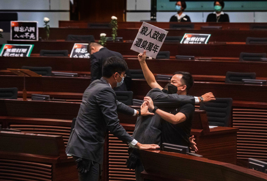 Pan-democratic legislator Chan Chi-chuen holding a placard reads &quot;A murderous regime stinks for ten thousand years&quot; scuffles with security guards at the main chamber of the Legislative Council dropping a pot of a pungent liquid in the chamber in Hong Kong, Thursday, June 4, 2020. A Hong Kong legislative debate was suspended Thursday afternoon ahead of an expected vote on a contentious national anthem bill after pro-democracy lawmakers staged a protest.(AP Photo/Chan Cheuk Fai/Initium) *** Hong Kong Out ***...