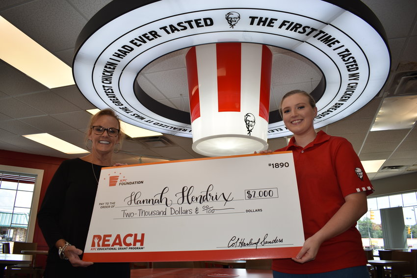 Sonya Parnell, left, the owner of the KFC in Jasper, presents a ceremonial $2,000 scholarship check from the REACH KFC Educational Grant Program to team member Hannah Hendrix on Thursday.