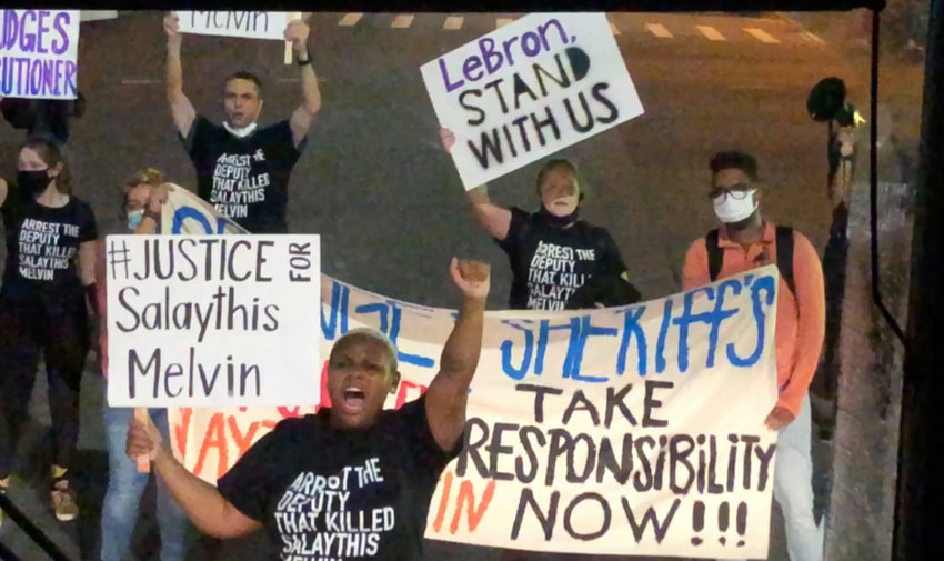 A small number of protesters of the August shooting in Central Florida of a Black man, Salaythis Melvin, hold signs and shout into megaphones, briefly blocking a bus chartered by the NBA from entering the Walt Disney World campus in Lake Buena Vista, Fla., Saturday night, Sept. 12, 2020, with the group saying it wanted LeBron James, Russell Westbrook and other top players to take notice. (AP Photo/Tim Reynolds)